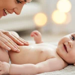 تصویر واقعی مادر در حال ماساژ ملایم نوزاد برای تقویت دلبستگی و خواب بهتر