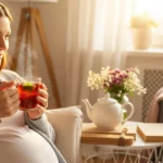 مادر باردار در سه‌ماهه سوم در حال نوشیدن دمنوش برگ تمشک سرخ برای آمادگی زایمان.